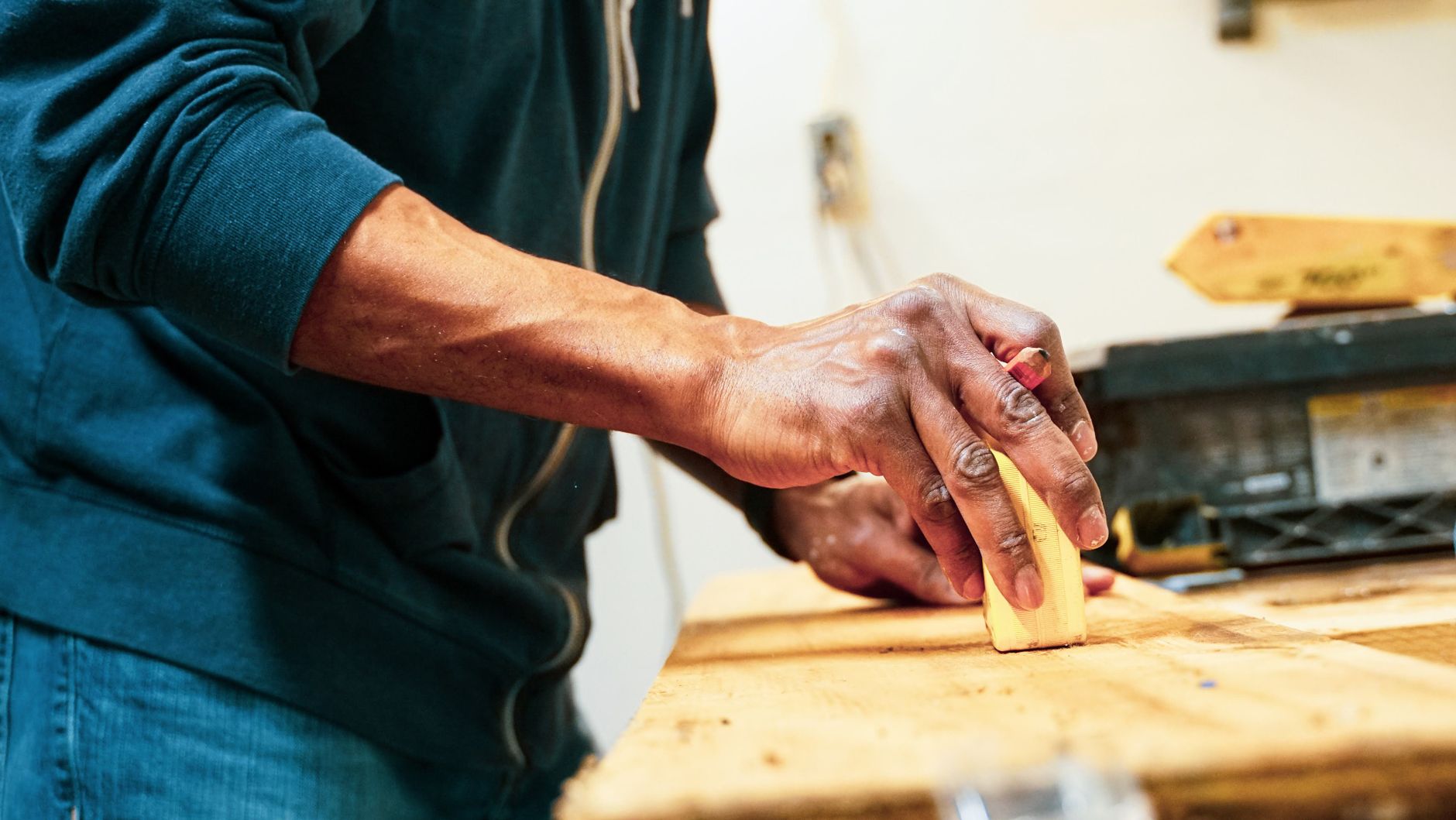 Hand schleift eine Massivholzfläche in einer Schreinerwerkstatt